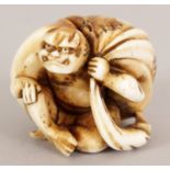 A JAPANESE MEIJI PERIOD STAINED IVORY NETSUKE OF A SQUATTING ONI, bearing behind him a large sack,