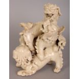 AN EARLY 20TH CENTURY CHINESE CREAM GLAZED PORCELAIN GROUP OF PLAYFUL BUDDHISTIC LIONS, 6.25in