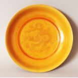 A CHINESE MING STYLE PORCELAIN DRAGON SAUCER DISH, applied with a yellow ochre glaze and incised