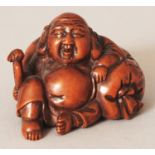 A JAPANESE CARVED WOOD NETSUKE OF HOTEI, seated reclining against his large bag, 1.9in wide & 1.