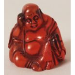 A SIGNED JAPANESE AMBER-LIKE NETSUKE OF HOTEI, seated and holding a fan, the base with an engraved