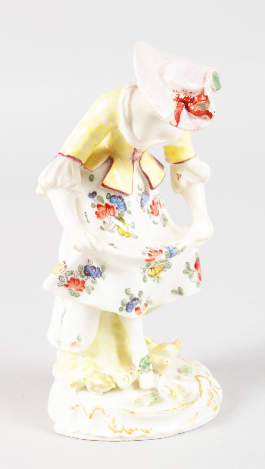 AN 18TH CENTURY RARE BOW FIGURE OF A GIRL FEEDING CHICKS, after a Meissen figure by Kaendler. 5ins