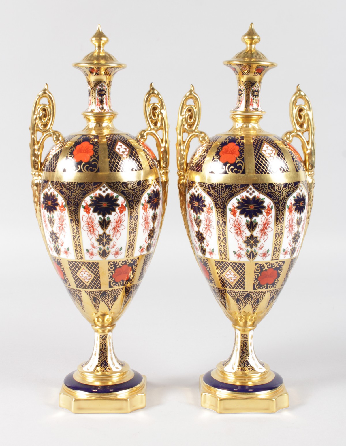A PAIR OF CROWN DERBY JAPAN PATTERN TWO HANDLED URNS AND COVERS. 12ins high.