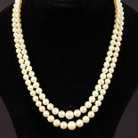 A SINGLE STRAND PEARL NECKLACE with gold and pearl clasp.