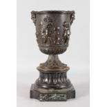 A 19TH CENTURY CLASSICAL BRONZE PEDESTAL URN decorated with a band of cupids and standing on a black