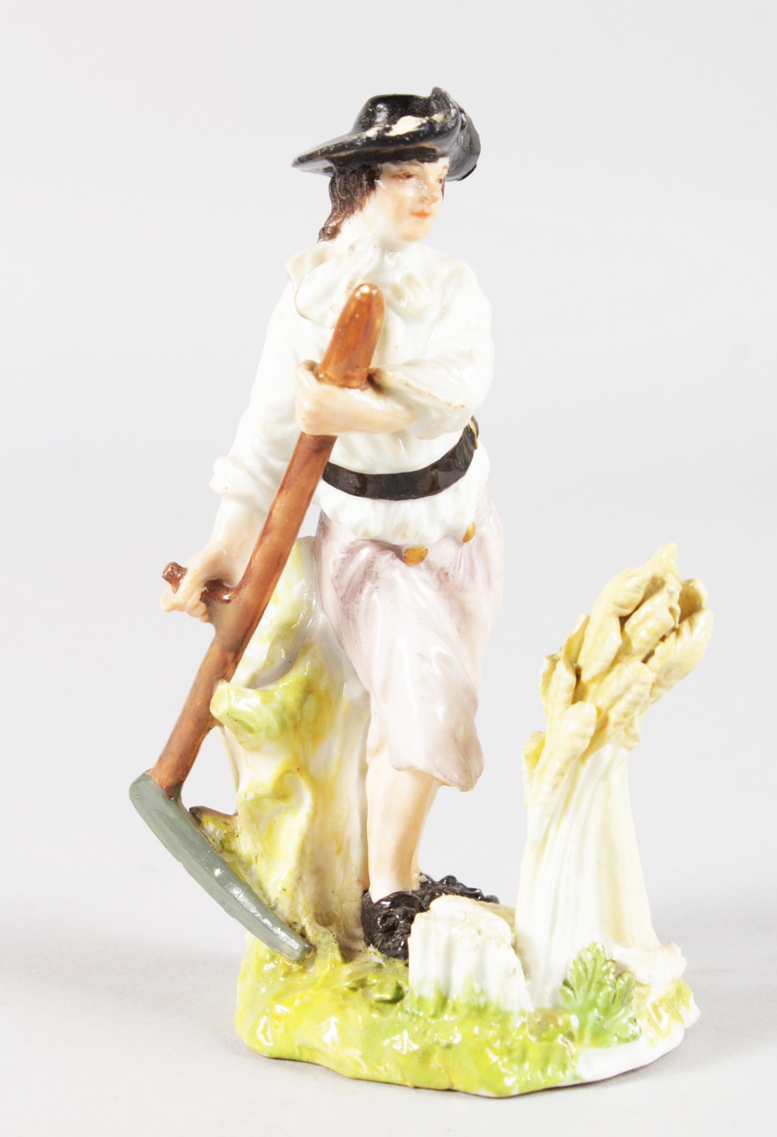 AN 18TH CENTURY MEISSEN FIGURE OF A HARVESTER with a scythe and corn, probably modelled by Kaendler,