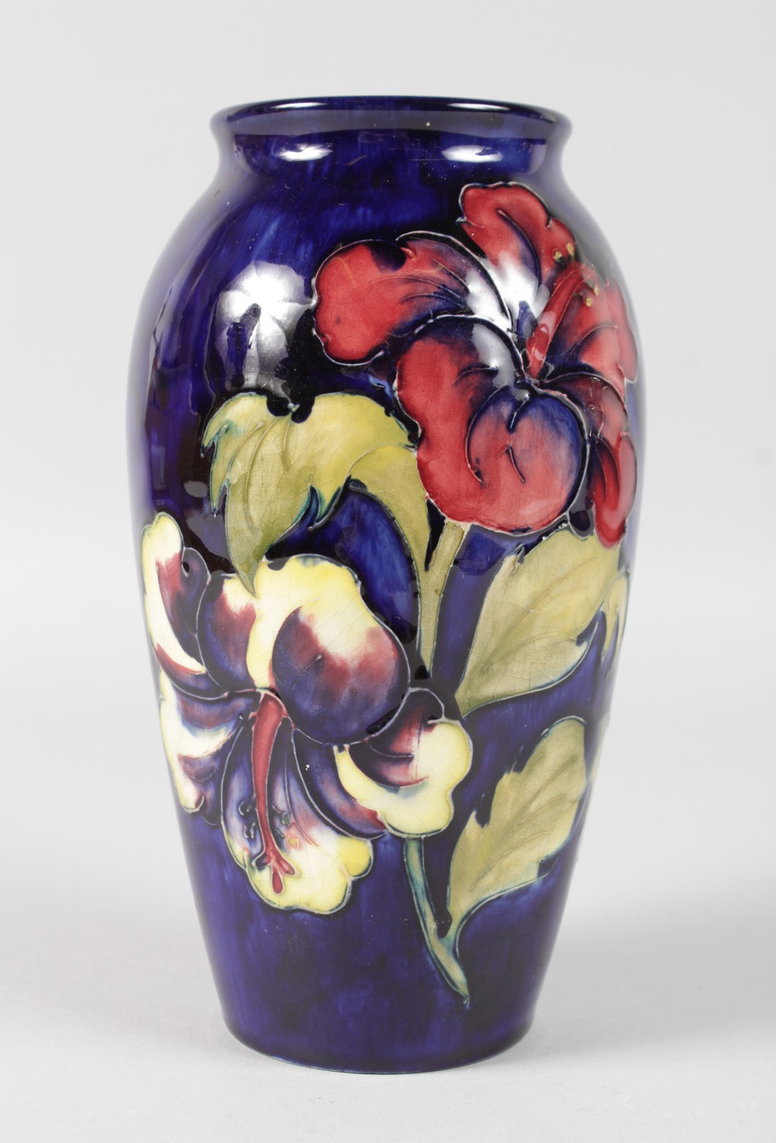 A MOORCROFT HIBISCUS PATTERNED VASE. Impressed MOORCROFT with printed label. 7.5ins high.