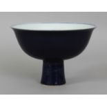 A CHINESE BLUE GLAZED PORCELAIN STEM BOWL, the sides decorated in faint white reserve with a