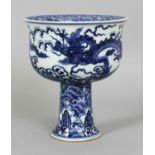 A CHINESE YUAN STYLE BLUE & WHITE PORCELAIN STEM BOWL, decorated with dragons above rocks and waves,