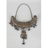 A LARGE & ELABORATE 19TH/20TH CENTURY INDIAN SILVER-METAL NECK AMULET, weighing 560gm, the curved