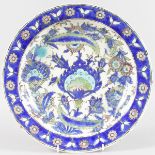 A 17TH CENTURY IZNIK POTTERY DISH, painted with flowers and motifs mainly in blue. 13.5ins
