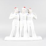 AN ART DECO DESIGN BLUE AND WHITE GROUP OF THREE SAILORS with red pom pom hats. 11ins high.