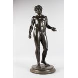 AFTER THE ANTIQUE A STANDING BRONZE FIGURE "NARCISSUS" standing on a circular base. 25.5ins high.