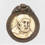 A RENAISSANCE CARVED IVORY PORTRAIT PENDANT "GREGOR XIII", 5cms diameter, in a bronze frame.