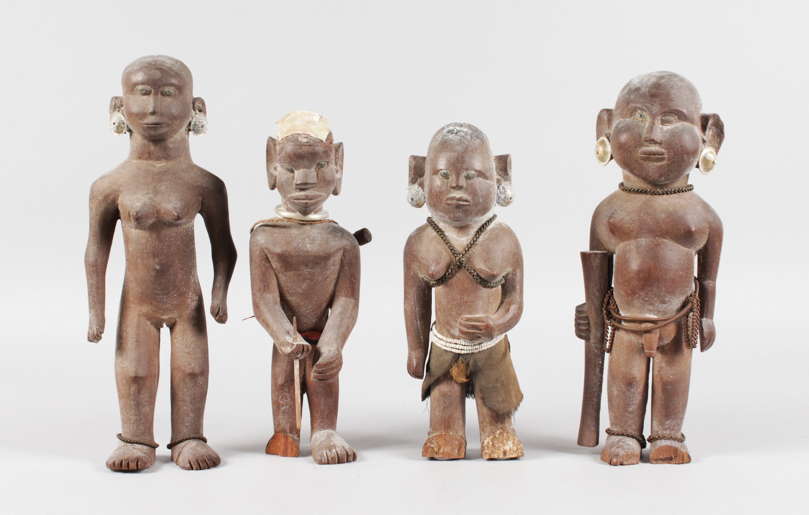 A SET OF FOUR ETHNIC CARVED WOOD TRIBAL FIGURES, some with original beadwork, 11ins high (2) and