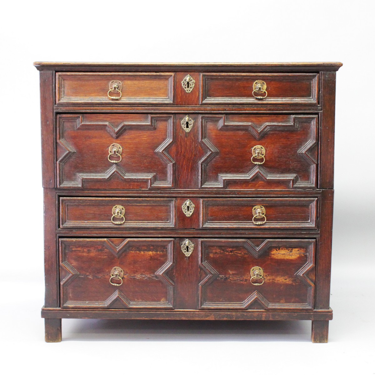 A 17TH CENTURY OAK CHEST OF DRAWERS, in two parts, with four long drawers, brass drop handles on