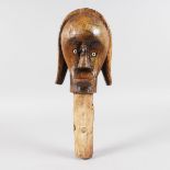 A TRIBAL HEAD with inlaid eyes. 12ins long.