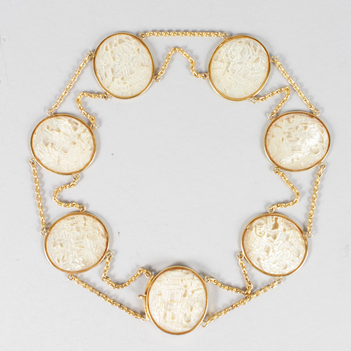 A SUPERB GOLD BRACELET set with SEVEN CARVED CHINESE MOTHER-OF-PEARL OVALS.