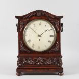 A LATE REGENCY MAHOGANY BRACKET CLOCK with large white circular dial, fretwork sides, carved