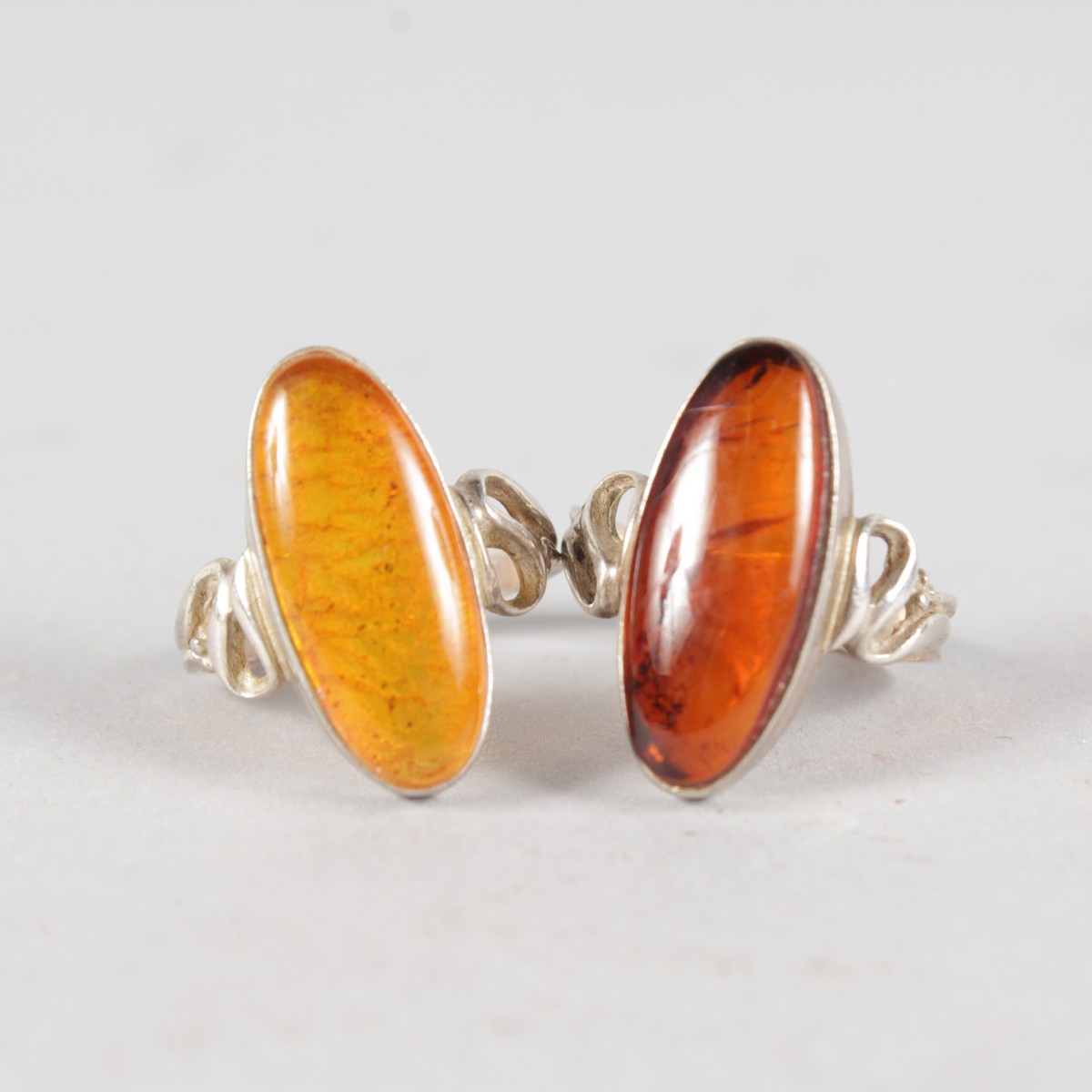 TWO SILVER AND AMBER RINGS.