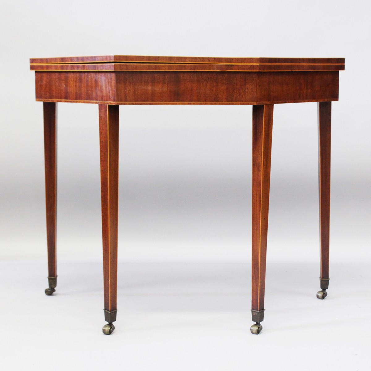 A GEORGE III MAHOGANY CARD TABLE, the fold-over top with crossbanded decoration on tapering square