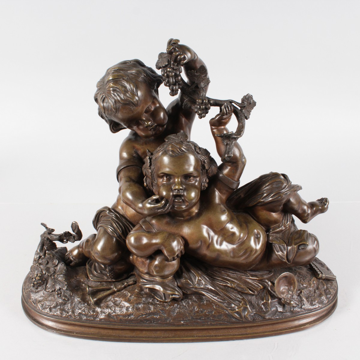 A GOOD 19TH CENTURY FRENCH BRONZE GROUP OF TWO YOUNG CUPIDS depicting harvest, holding grapes. 15ins