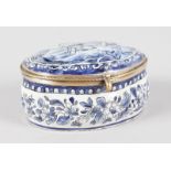 A DELFT WARE OVAL BLUE AND WHITE BOX AND COVER, the lid with figures merrymaking. 4ins long.