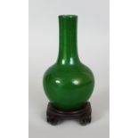 AN 18TH CENTURY CHINESE APPLE GREEN CRACKLEGLAZE PORCELAIN BOTTLE VASE, together with a carved