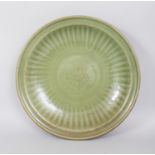 A LARGE CHINESE MING DYNASTY LONGQUAN CELADON STONEWARE DISH, the interior lightly moulded beneath