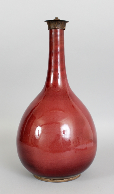 A CHINESE 18TH CENTURY SANG-DE-BOEUF PORCELAIN BOTTLE VASE, with a fixed bronze neck fitting, the