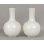 A PAIR OF 18TH/19TH CENTURY CHINESE WHITE GLAZED PORCELAIN BOTTLE VASES, each decorated in white