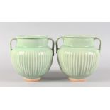 A PAIR OF GREEN FLUTED TWO HANDLED BULBOUS VASES. 7.5ins high.