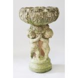 A COMPOSITION CHRYSANTHEMUM PATTERN BIRD BATH. the top supported by three cupids, on a circular