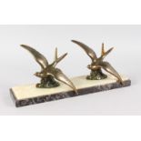 AN ART DECO GROUP OF TWO GILT FLYING BIRDS on a two colour marble base. 16ins long.