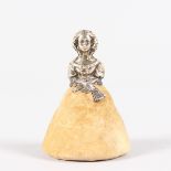 A YOUNG LADY PIN CUSHION, with silver head and shoulders and carrying a fan. 6.5cms high. Birmingham