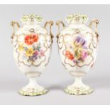 A PAIR OF CONTINENTAL EGG SHAPED TWO HANDLED VASES, painted with flowers and gilt ribbons. 20cms