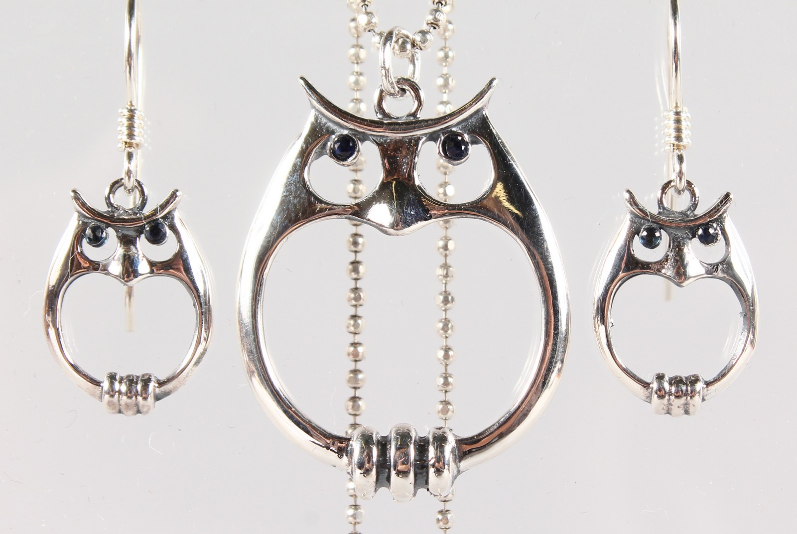 A SILVER SAPPHIRE SET PENDANT AND EARRINGS AS OWLS