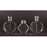 THREE PLAIN GLASS SCENT BOTTLES with silver tops.