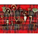 A COLLECTION OF SEVENTEEN VICTORIAN AND EDWARDIAN HAT PINS on a tartan cloth.