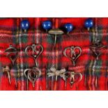 A COLLECTION OF FOURTEEN VICTORIAN AND EDWARDIAN HAT PINS on a tartan cloth.