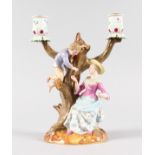 A GOOD MEISSEN TWO BRANCH CANDELABRA, a young boy up a tree passing bird eggs to a lady. Cross