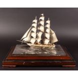 A STERLING SILVER MODEL OF A THREE MASTED SAILING BOAT, 11.5ins long, 10ins high, standing on a