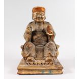 A CHINESE CARVED WOOD AND GILDED SEATED DEITY, seated on a stool. 16ins high.