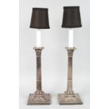 A PAIR OF SILVER PLATED CLASSICAL CANDLESTICKS with Corinthian columns on square loaded bases. 12ins