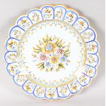 A LARGE SPANISH CIRCULAR SHAPED DELFT WARE DISH painted with flowers. 15ins diameter.