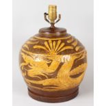 A LARGE BROWN POTTERY BULBOUS LAMP decorated with sea serpents. 9ins x 9ins, on a wooden base.