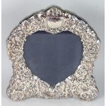 A STERLING SILVER UPRIGHT SHAPED EASEL MIRROR repousse with scrolls, winged cupids etc. 11ins