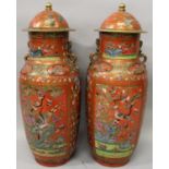 A GOOD LARGE PAIR OF 19TH CENTURY CHINESE CANTON FAMILLE ROSE CORAL GROUND PORCELAIN VASES & COVERS,