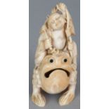 AN UNUSUAL IVORY CARVING OF BUDAI SEATED ON THE BACK OF THE THREE-LEGGED TOAD, the deity holding a