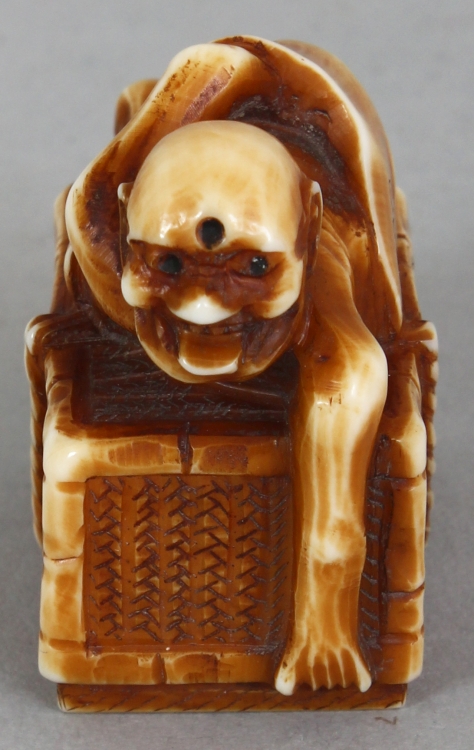 A SIGNED JAPANESE MEIJI PERIOD STAINED IVORY NETSUKE OF A DEMON, lying astride a rectangular reed - Image 2 of 9